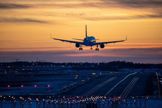 Airplane landing to airport runway in sunset