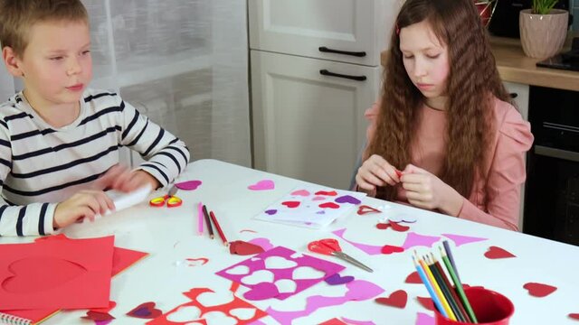 Kids, children, doing Valentine's Day arts and crafts with hearts, pencils, paper. Gift, surprize for mom. Children makes Handmade decorations for holiday. Prepare for Valentine Day. Painting, DIY.