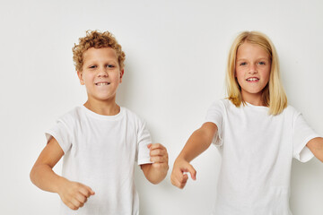 Portrait of cute children in white T-shirts are standing next to childhood unaltered