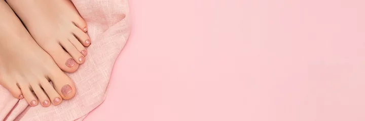 Foto auf Acrylglas Pediküre Weibliche Füße mit rosa Nageldesign. Glitter rosa Nagellack Pediküre auf hellrosa Hintergrund. Weibliche Füße mit perfekter Frühlingspediküre. Werbebanner.