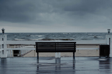 Fototapeta na wymiar A lonely empty bench by the sea in a storm
