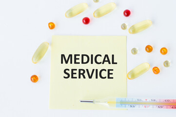 White card with the text Medical Services next to it lies a thermometer and scattered multi-colored pills