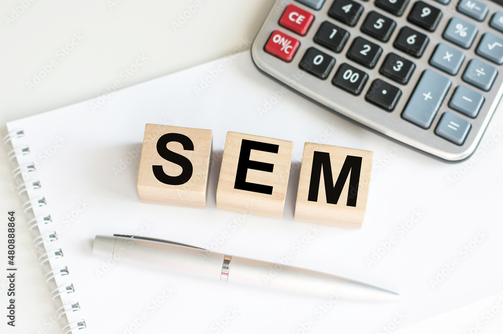 Aufkleber sem word on wooden cubes on a notebook next to a calculator and a pen on the table
