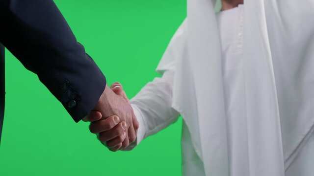 Arab man in a white kandura makes a good deal with a partner buisnessman in a suit, a handshake between two buisnessman, chromakey template.