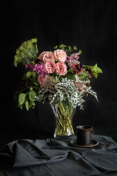 Studio shot of coffee cup and bouquet of Mini Eden roses, annual claries, Queen Annes lace, black-eyed Susans, silver ragwort, mint and dill