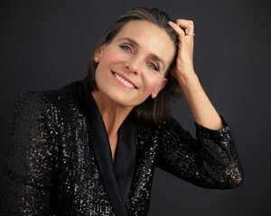 Beautiful mature woman wearing black dress with hand in hair