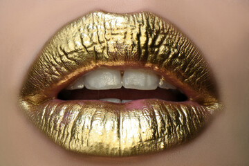 Gold lips. Gold paint from the mouth. Golden lips on woman mouth with make-up. Sensual and creative design for golden metallic. Golden design. - obrazy, fototapety, plakaty