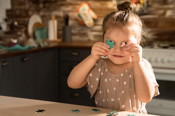 Little preschool playing with puzzle in kitchen at home