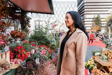 Smiling woman with overcoat at flower shop in Christmas market