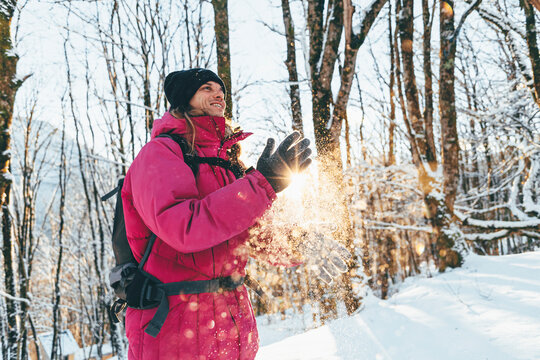 Smiling tourist dusting snow from hands in forest