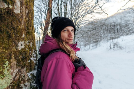 Tourist standing by tree trunk in winter vacation