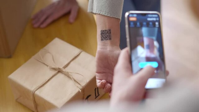 Cropped shot of courier deliver parcel and scan customer qr-code tattoo. Realtime