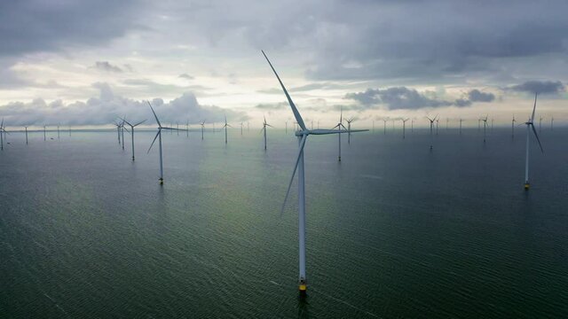 Drone video of the offshore wind turbine at Fryslan wind farm in the IJsselmeer. Dark rain clouds in the sky. Sustainable development, renewable energy, environment concept. Breezanddijk, Netherlands
