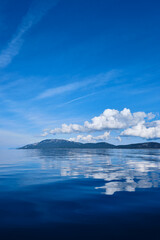 Fototapeta na wymiar blue sky with clouds and island with water reflection