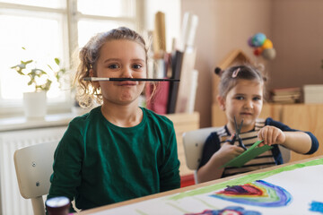 Happy little girl with her friends preparing for art class indoors at school