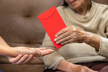 Grandmother hand giving a red envelope or hongbao to kids on chinese new year celebration.