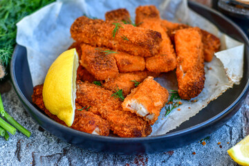 Close up of   Crispy breaded  deep fried fish fingers with breadcrumbs served  with remoulade sauce and  lemon Cod Fish Nuggets on rustic wood table background
