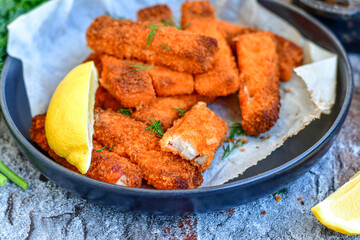 Close up of   Crispy breaded  deep fried fish fingers with breadcrumbs served  with remoulade sauce and  lemon Cod Fish Nuggets on rustic wood table background