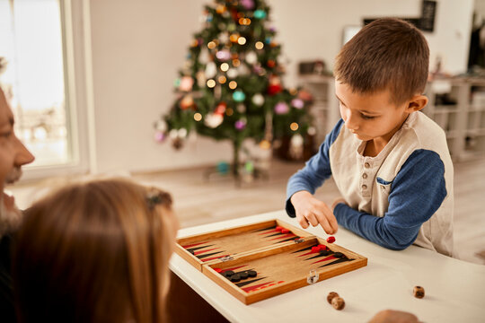 Boy throwing dice playing backgammon at home