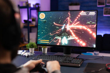 Man playing video games with joystick on computer. Player using controller and wearing headphones...