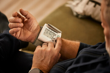 Senior man checking blood pressure at home