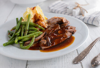 Plate with roast meat, gravy, mashed potatoes and green beans