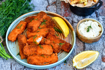 Close up of   Crispy breaded  deep fried fish fingers with breadcrumbs served  with remoulade sauce and  lemon Cod Fish Nuggets on rustic wood table background