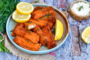 Close up of   Crispy breaded  deep fried fish fingers with breadcrumbs served  with remoulade sauce and  lemon Cod Fish Nuggets on rustic wood table background