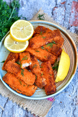 Close up of   Crispy breaded  deep fried fish fingers with breadcrumbs served  with remoulade sauce and  lemon Cod Fish Nuggets on rustic wood table background