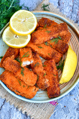 Close up of   Crispy breaded  deep fried fish fingers with breadcrumbs served  with remoulade sauce and  lemon Cod Fish Nuggets on rustic wood table background