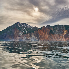 Mountains and volcanoes of Kamchatka against the backdrop of a beautiful sea and clouds at sunset. Kamchatka, Russia. Travel and tourism in the mountains