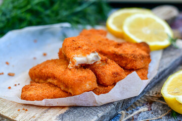 Close up of   Crispy breaded  deep fried fish fingers with breadcrumbs served  with remoulade sauce and  lemon Cod Fish Nuggets on rustic wood table background