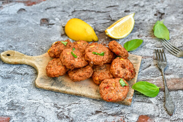 Home made  pork meatballs with  fresh cherry tomatoes on wooden rustic background. Deep fried minced  meat patties on cutting board.