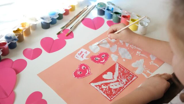 Child created homemade greeting card. A little girl painted and colored card with funny hearts. Gift for Mothers Day or Valentines day. Arts and crafts concept.