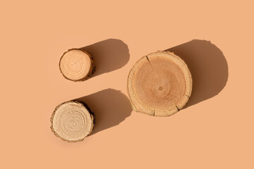 Three wooden disks lying on a trendy beige background. A platform made of trees for luxury and...