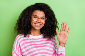 Portrait of attractive cheerful friendly girl nerd waving hi hello congrats isolated over bright green color background © deagreez