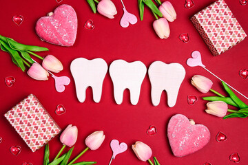 White teeth surrounded by gifts, hearts and tulip flowers on a red background.