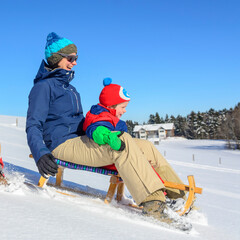 Mutter und Kind haben Spass beim Rodeln an einem sonnigen Wintertag