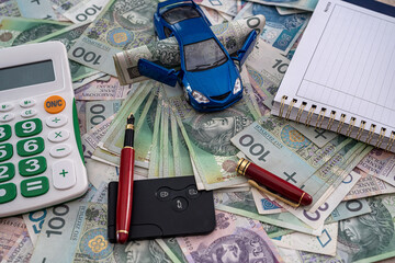 a large sum of Polish zlotys is tied with an elastic band next to car keys and a toy car.
