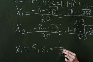 schoolgirl writing high school maths formula  with chalk on blackboard © RomanR