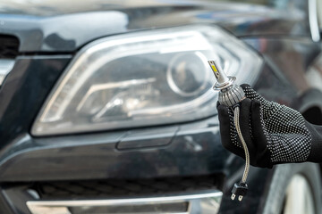 mechanic installing modern led H7 light bulb with wires in headlamp