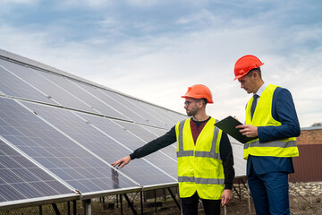 two professionals in workwear discuss solar panels and their impact.