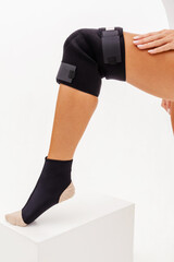 The female leg is wearing an ankle brace and orthopedic knee support