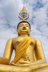 Obraz premium Low angle view of golden buddha statue on blue sky with clouds background at historic ancient Wat Chiang Yuen buddhist temple, Chiang Mai, Thailand
