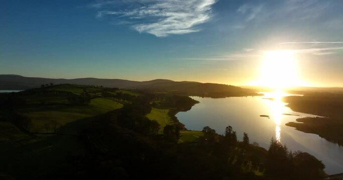 Blessington Lakes, Wicklow, Ireland. January 2022 Drone pulls across Boystown from the north above the Poulaphouca reservoir with a golden wintery sunset on the horizon.
