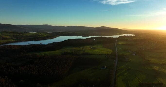 Blessington Lakes, Wicklow, Ireland. January 2022 Drone pulls northwest across from the Poulaphouca reservoir above Burgage Moyle with a golden wintery sunset on the horizon.