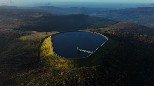 Turlough Hill, Wicklow, Ireland. January 2022 Drone gradually orbits the upper Reservoir from the southeast on a bright wintery afternoon with Mullaghcleevaun mountain and Blessington in the distance.