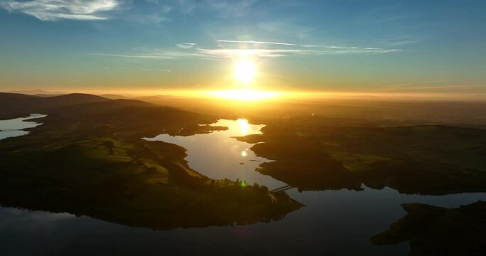 Blessington Lakes, Wicklow, Ireland. January 2022 Drone pushes towards Boystown above the Poulaphouca reservoir while descending from the northeast with a golden wintery sunset on the horizon.