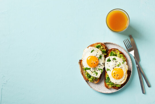 Healthy breakfast with eggs toast and orange juice on blue background