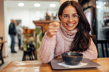 Smiling woman with glasses, eating at a restaurant and enjoying.